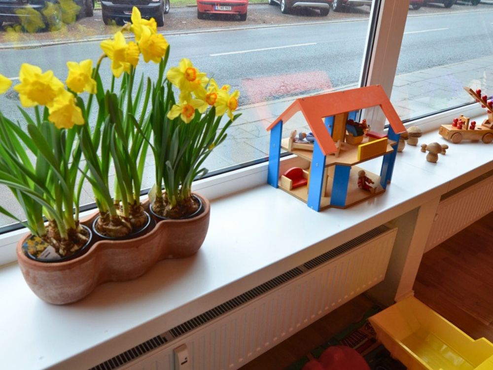 Fensterbank mit Blumen, Holzspielzeug und Blick nach draußen