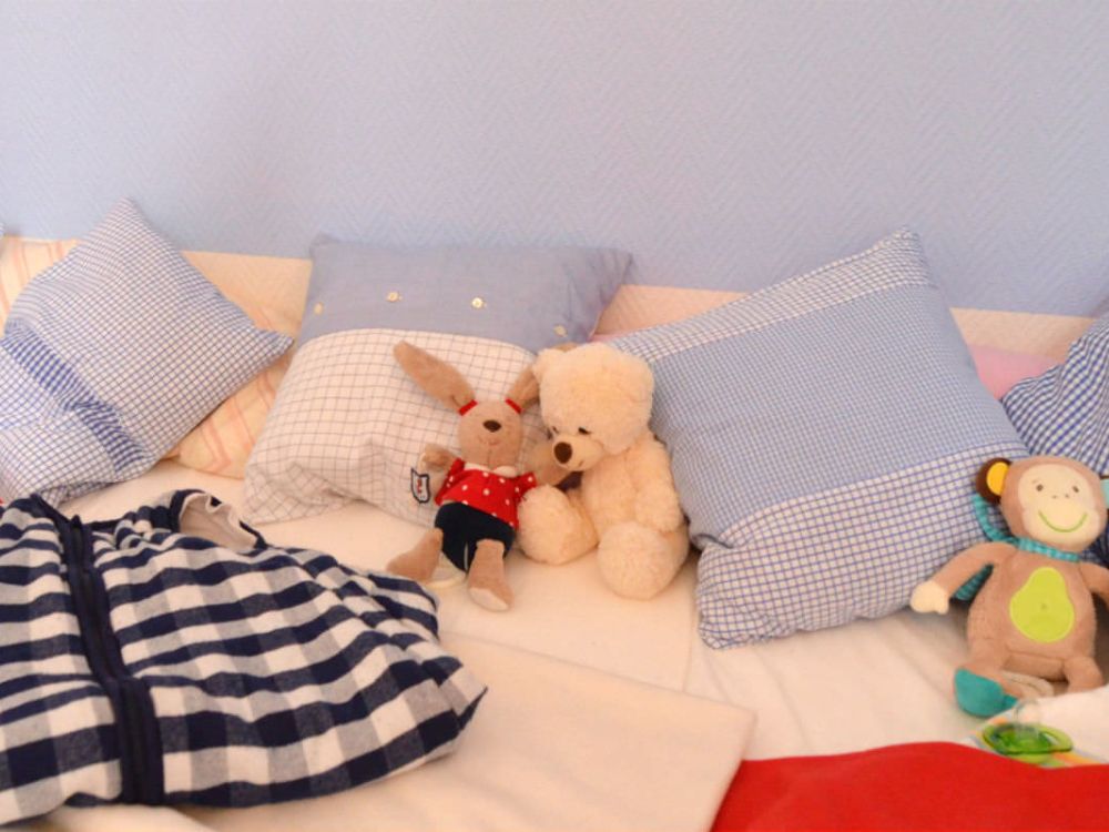 Gemütlicher Schlafbereich mit Kissen, Decken und Kuscheltieren